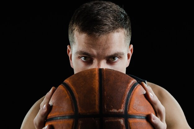 Jugador de baloncesto cubriendo su cara con una pelota