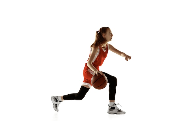 Jugador de baloncesto femenino caucásico joven en acción, movimiento en funcionamiento aislado en el fondo blanco. Chica deportiva pelirroja. Concepto de deporte, movimiento, energía y estilo de vida dinámico y saludable. Capacitación.