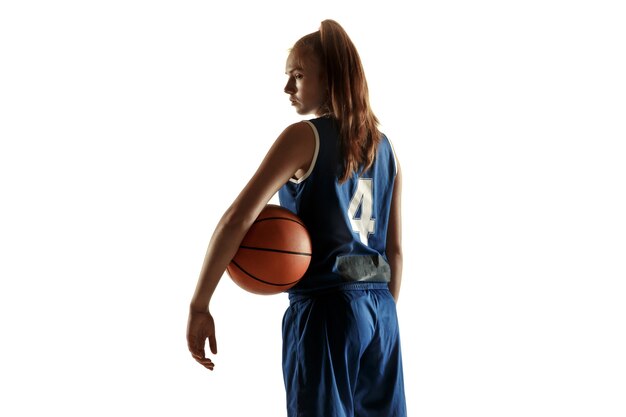 Jugador de baloncesto femenino caucásico joven del equipo que presenta confiado con el balón aislado en el fondo blanco.