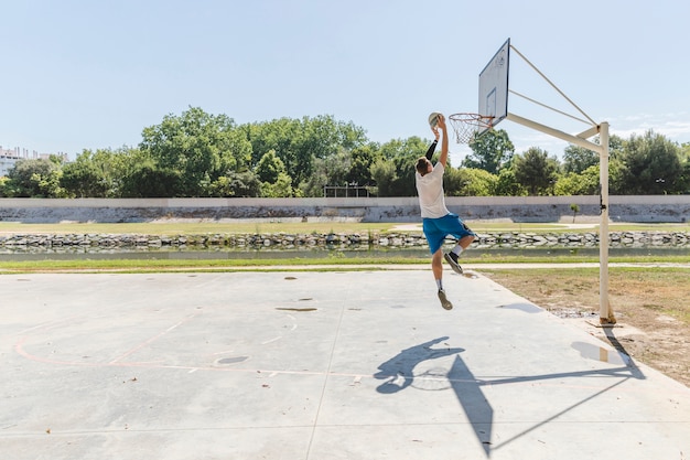 Foto gratuita jugador de baloncesto lanzando baloncesto en el aro