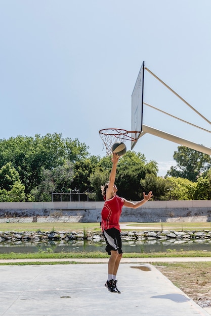 Jugador de baloncesto lanzando la pelota en el aro en la cancha al aire libre