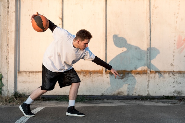 Jugador de baloncesto lateral en cancha urbana