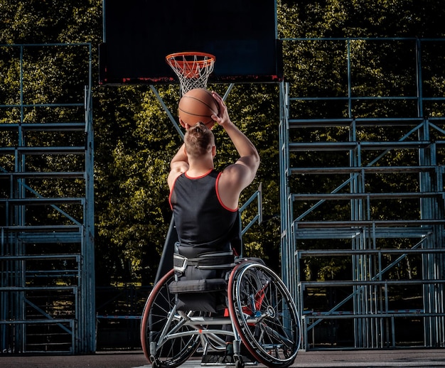 Un jugador de baloncesto lisiado en silla de ruedas juega en un campo de juego abierto.