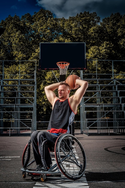 Foto gratuita un jugador de baloncesto lisiado en silla de ruedas juega en un campo de juego abierto.