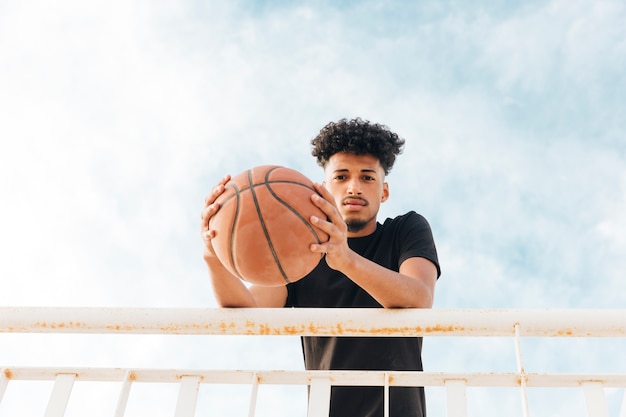 Foto gratuita jugador de baloncesto con pelota mirando a cámara