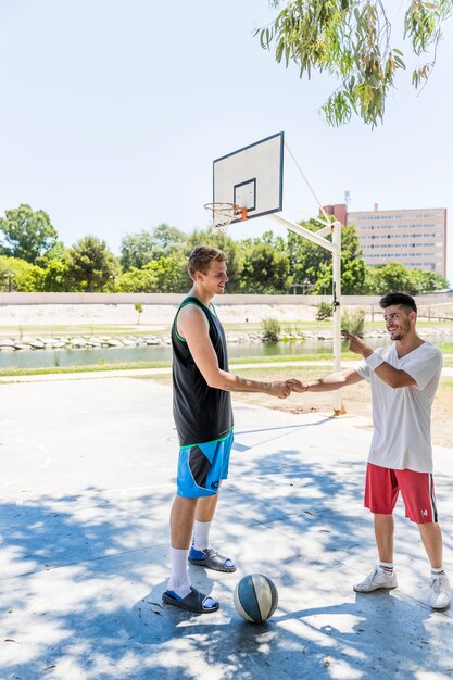 Jugador de baloncesto sacudiendo la mano del otro en cancha de baloncesto al aire libre