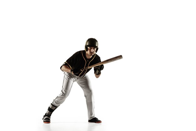 Jugador de béisbol, lanzador con uniforme negro practicando y entrenando aislado en una pared blanca. Joven deportista profesional en acción y movimiento. Estilo de vida saludable, deporte, concepto de movimiento.