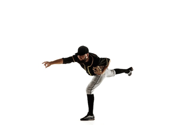 Jugador de béisbol, lanzador con uniforme negro practicando y entrenando aislado en una pared blanca. Joven deportista profesional en acción y movimiento. Estilo de vida saludable, deporte, concepto de movimiento.