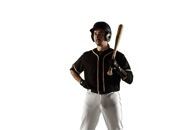 Jugador de béisbol, lanzador con uniforme negro practicando y entrenando aislado en una pared blanca. Joven deportista profesional en acción y movimiento. Estilo de vida saludable, deporte, concepto de movimiento.