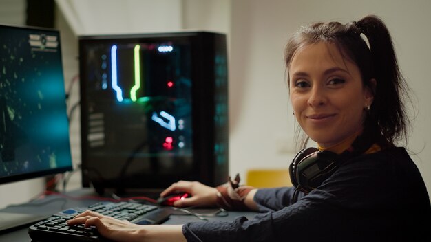 Jugador concentrado mirando a la cámara mientras juega un videojuego en línea de disparos espaciales en una poderosa computadora personal RGB durante el campeonato de egames. Esport cyber actuando durante el torneo de juegos