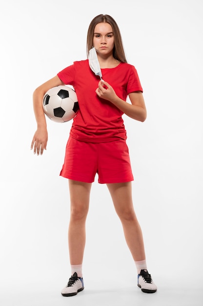 Jugador de fútbol femenino con máscara sosteniendo bola