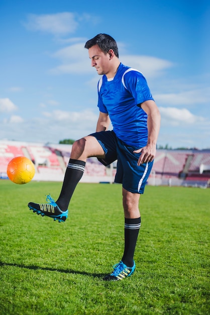 Foto gratuita jugador de fútbol haciendo dominadas en arena