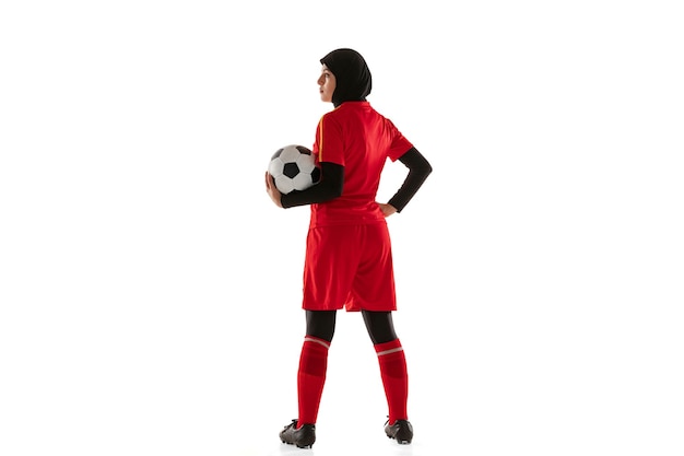 Jugador de fútbol o fútbol femenino árabe aislado sobre fondo blanco de estudio. Mujer joven sosteniendo la pelota, entrenando, practicando en movimiento y acción.