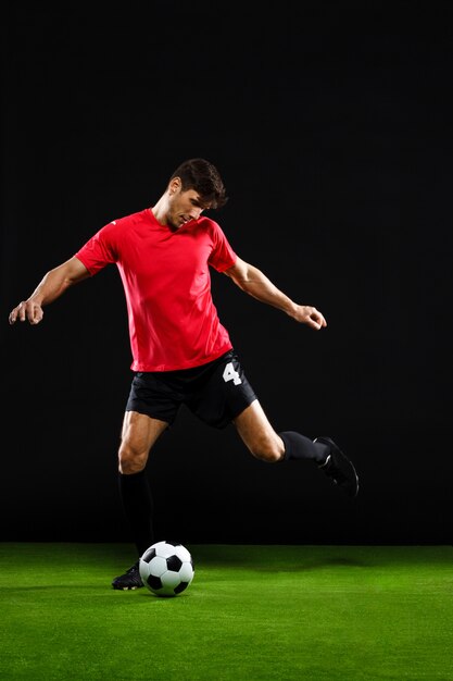 Jugador de fútbol pateando la pelota, jugar al fútbol en el campo