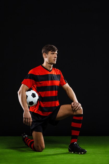 Jugador de fútbol con pelota de pie sobre la rodilla, jugar al fútbol