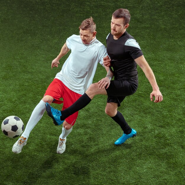 Jugador de fútbol que aborda la pelota sobre fondo de hierba verde.