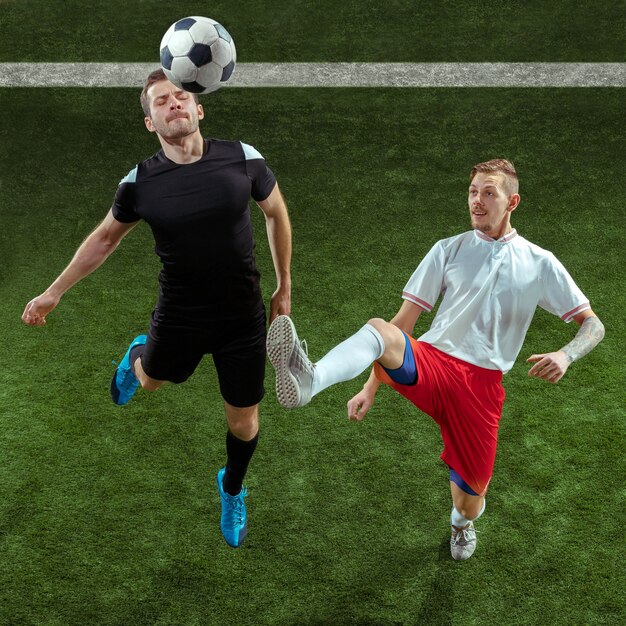 Jugador de fútbol que aborda la pelota sobre fondo de hierba verde.
