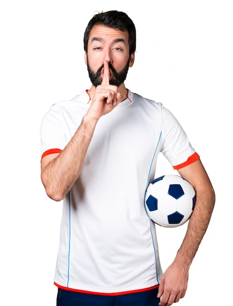 Foto gratuita jugador de fútbol que sostiene un balón de fútbol que hace gesto del silencio