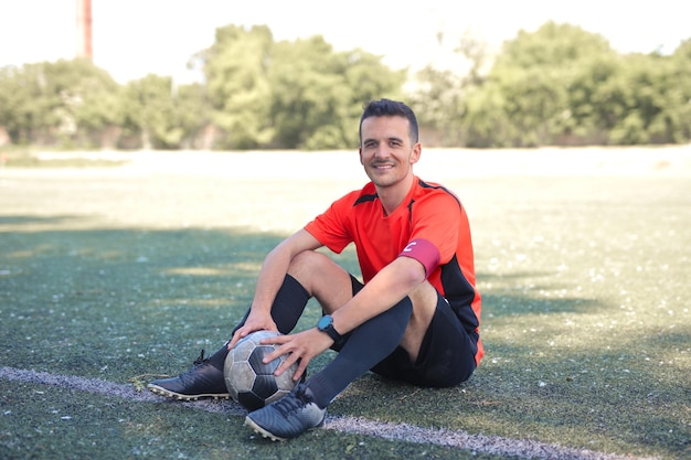 Foto gratuita jugador de fútbol sentado en el campo de juego