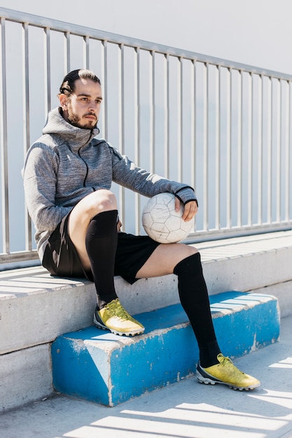 Jugador de fútbol sentado con pelota