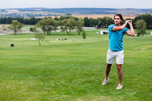 Jugador de golf masculino de tiro largo en campo de golf profesional