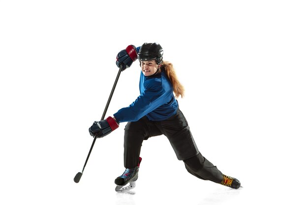 Jugador de hockey femenino joven con el palo en la cancha de hielo y la pared blanca. Deportista con equipo y entrenamiento de casco. Concepto de deporte, estilo de vida saludable, movimiento, acción, emociones humanas.