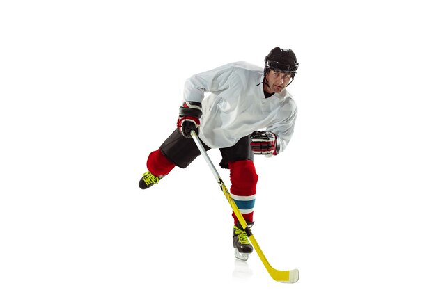 Jugador de hockey masculino joven con el palo en la cancha de hielo y fondo blanco.