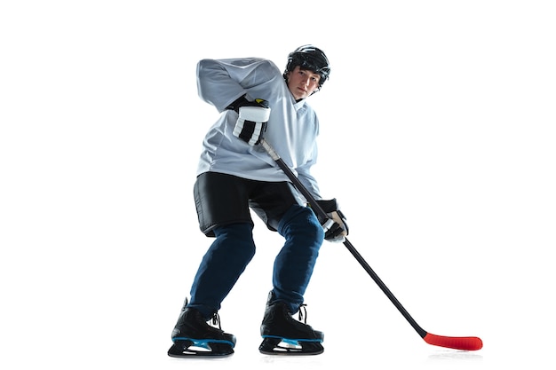 Jugador de hockey masculino joven con el palo en la cancha de hielo