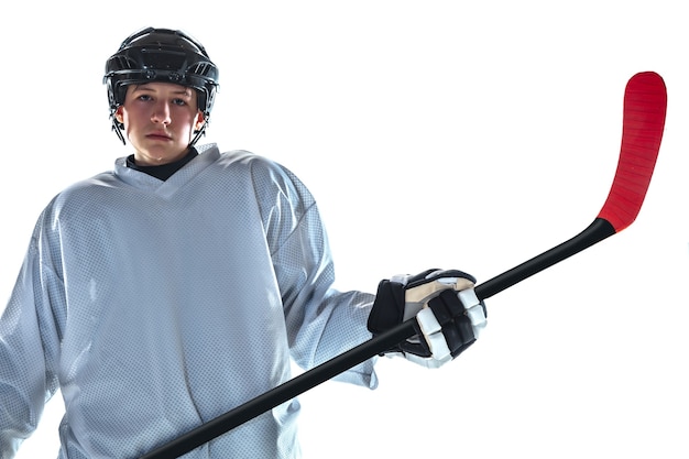 Foto gratuita jugador de hockey masculino joven serio con el palo en la cancha de hielo y la pared blanca