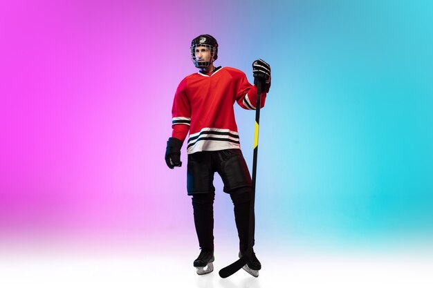 Jugador de hockey masculino con el palo en la cancha de hielo y el espacio degradado de neón