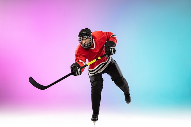 Jugador de hockey masculino con el palo en la cancha de hielo y fondo degradado de color neón