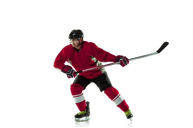 Jugador de hockey masculino con el palo en la cancha de hielo y pared blanca