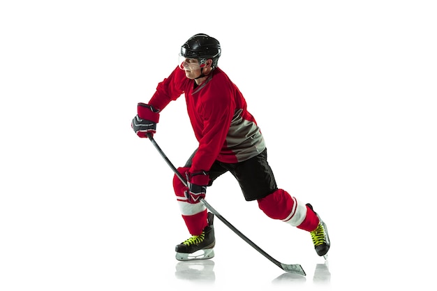 Jugador de hockey masculino con el palo en la cancha de hielo y pared blanca