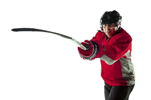 Jugador de hockey masculino con el palo en la cancha de hielo y pared blanca