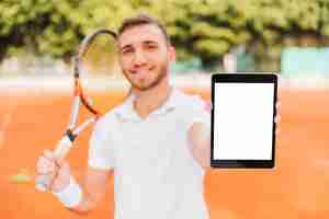 Foto gratuita jugador joven atlético de tenis enseñando una tablet