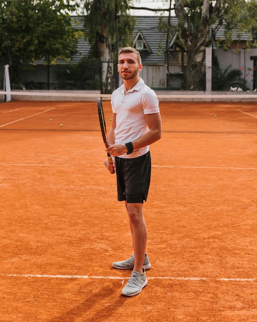 Jugador joven atlético de tenis posando