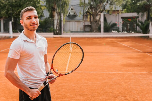 Jugador joven atlético de tenis posando