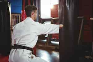 Foto gratuita jugador de karate golpeando una bolsa de boxeo