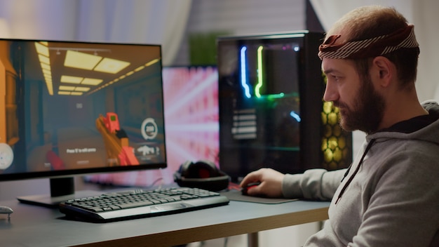 Jugador profesional de deportes electrónicos mirando a la cámara sonriendo mientras compite en un videojuego que juega al juego de disparos espaciales. Transmisión cibernética en línea que se realiza en una potente computadora personal durante el torneo de juegos