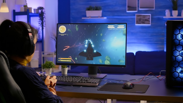 Jugador profesional que juega al campeonato en línea de disparos espaciales con gráficos modernos usando un controlador inalámbrico