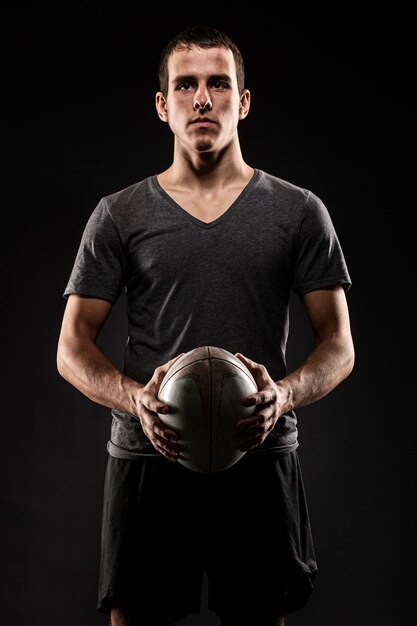 Jugador de rugby masculino atlético guapo sosteniendo la bola