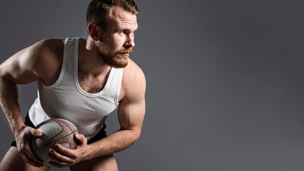 Jugador de rugby masculino guapo sosteniendo la bola con espacio de copia