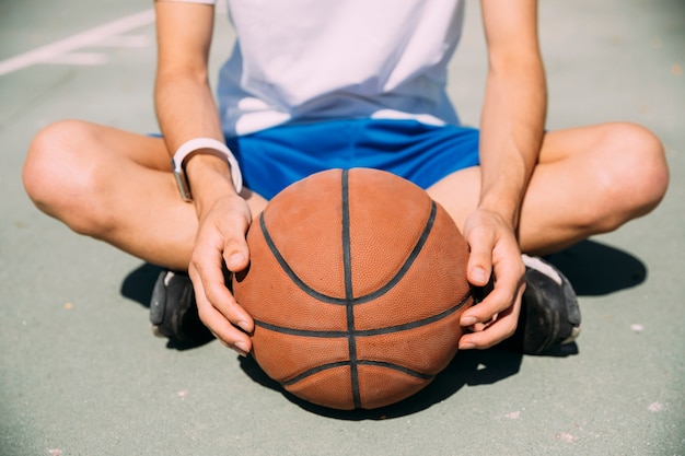 Jugador sosteniendo baloncesto mientras está sentado en el patio