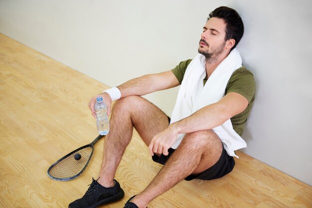 Jugador de squash agotado descansando en el piso