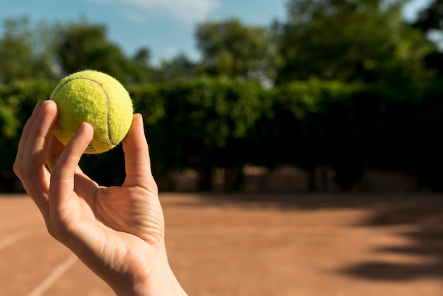 Jugador de tenis agarrando una pelota de tenis