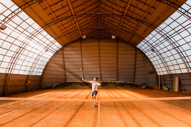 Jugador de tenis saqueando en sala