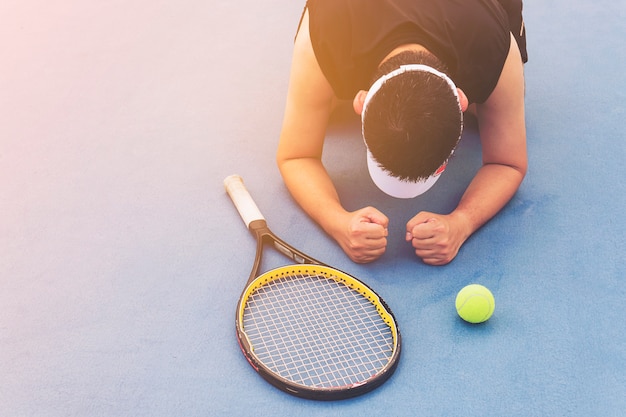 Jugador de tenis triste sentado en la cancha después de perder un partido