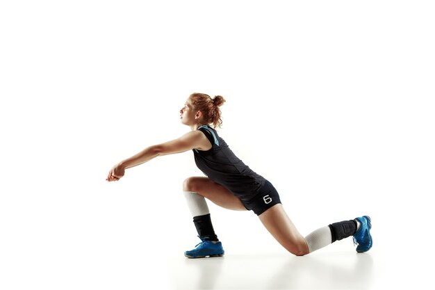 Jugador de voleibol femenino joven aislado en la pared blanca. Mujer en equipamiento deportivo y zapatos o zapatillas de deporte entrenando y practicando. Concepto de deporte, estilo de vida saludable, movimiento y movimiento.