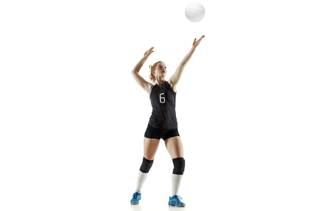 Jugador de voleibol femenino joven aislado en la pared blanca. Mujer en equipamiento deportivo y zapatos o zapatillas de deporte entrenando y practicando. Concepto de deporte, estilo de vida saludable, movimiento y movimiento.