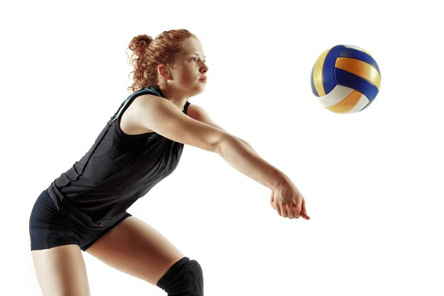 Jugador de voleibol femenino joven aislado sobre fondo blanco de estudio. Mujer en equipamiento deportivo y zapatos o zapatillas de deporte entrenando y practicando. Concepto de deporte, estilo de vida saludable, movimiento y movimiento.